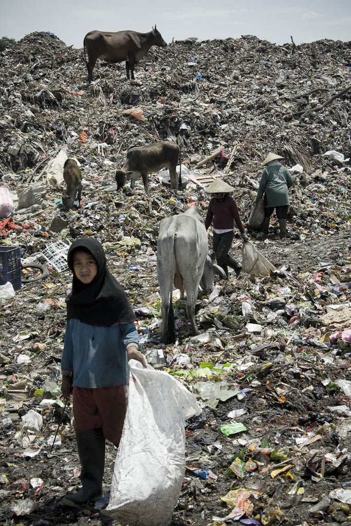 A girl armed with a hook faces up the day unwillingly. Makkasar dump. Indonesia.